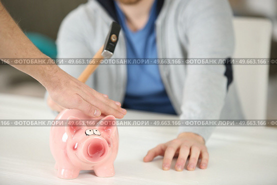 hand stopping person from breaking piggybank with hammer. Стоковое фото, агентство Ingram Publishing / Фотобанк Лори