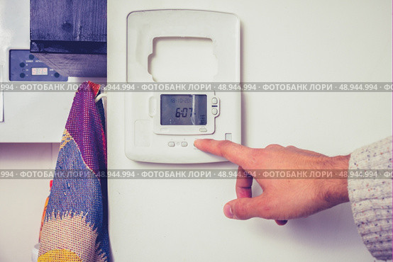 Hand touching thermostat. Стоковое фото, агентство Ingram Publishing / Фотобанк Лори