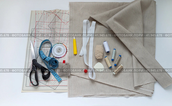 Handicrafts and sewing clothes at home. Drawings of patterns for sewing summer clothes from natural linen fabric and sewing accessories on a white desktop. Flat lay, close-up, top view, copy space, mockup. Стоковое фото, фотограф Виктория Катьянова / Фотобанк Лори