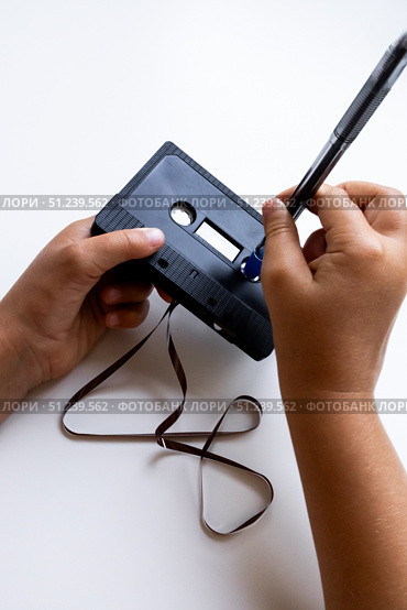 Hands adjusting cassette tape with pen for rewinding. Стоковое фото, фотограф Lamina Akulova / Фотобанк Лори