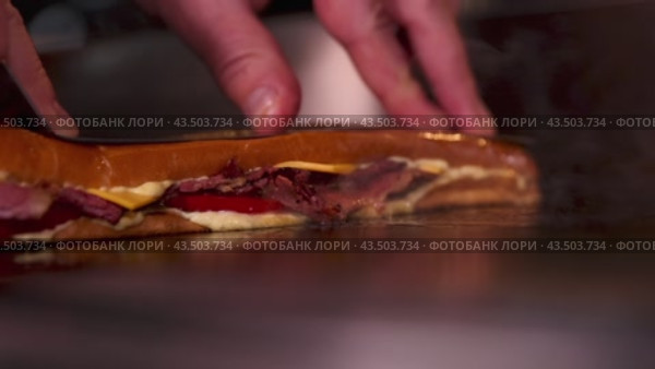 Hands are actively involved in the preparation of a flavorful sandwich on a hot griddle. Стоковое видео, видеограф Victor Kaprov / Фотобанк Лори