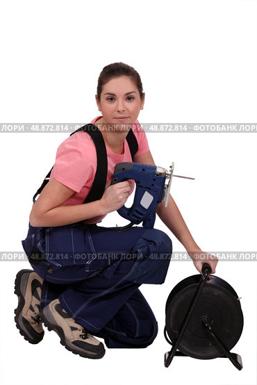 Handywoman holding a jigsaw and an extension cord. Стоковое фото, агентство Ingram Publishing / Фотобанк Лори