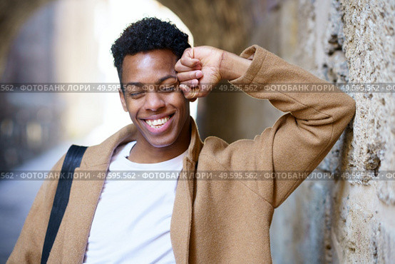 Happy black man laughing outdoors. Cuban student in urban background.. Happy young black man laughing in urban background. Стоковое фото, агентство Ingram Publishing / Фотобанк Лори