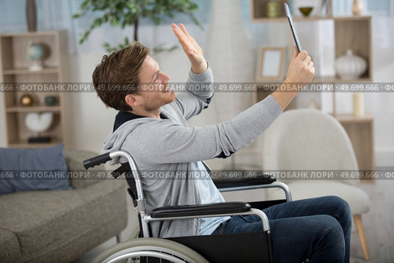 happy crippled man holding a tablet and waving. Стоковое фото, агентство Ingram Publishing / Фотобанк Лори