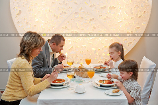 Happy family enjoying meal sitting at re. Стоковое фото, фотограф Roberts Ratuts / Smarterpix / Фотобанк Лори