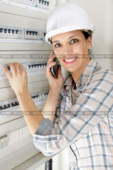 happy female repairer on the phone fixing fuses. Стоковое фото, агентство Ingram Publishing / Фотобанк Лори