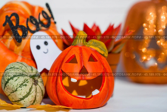 Happy Halloween! Pumpkin Jack on the table. Lantern with a carved smile and different attributes of the holiday on a light background.A copy of the place for the text. Стоковое фото, фотограф Photojuli / Фотобанк Лори