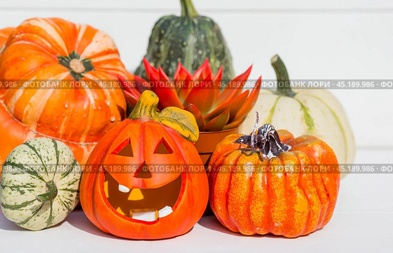 Happy Halloween! Pumpkin Jack on the table. Lantern with a carved smile and different attributes of the holiday on a light background.A copy of the place for the text. Стоковое фото, фотограф Photojuli / Фотобанк Лори