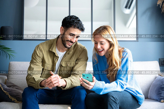 Happy man and woman have fun browsing the internet on a smartphone. Стоковое фото, фотограф Raquel Corcoles Mendez / Фотобанк Лори