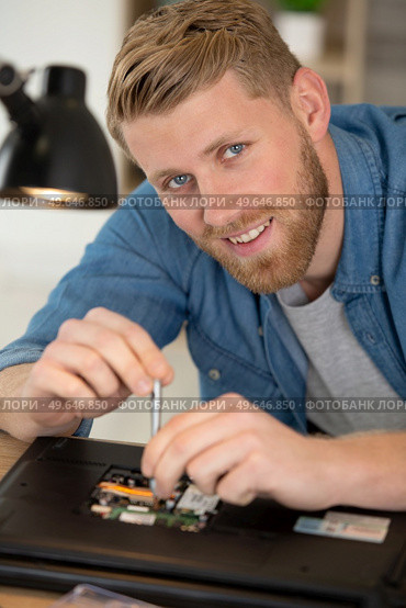 happy man using screwdriver and repairing a broken laptop. Стоковое фото, агентство Ingram Publishing / Фотобанк Лори