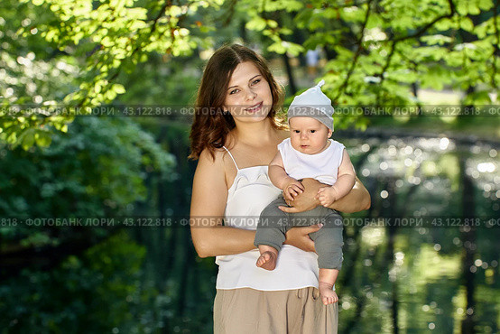 Happy mother holds child while walks in park on summer. Стоковое фото, фотограф Владимир Григорьев / Фотобанк Лори