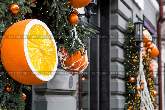 Happy New Year 2026. Mandarins in a string bag and Christmas tree decorations on the streets of Moscow. The concept of preparing decorations and ornaments for Christmas. Стоковое фото, фотограф Photojuli / Фотобанк Лори