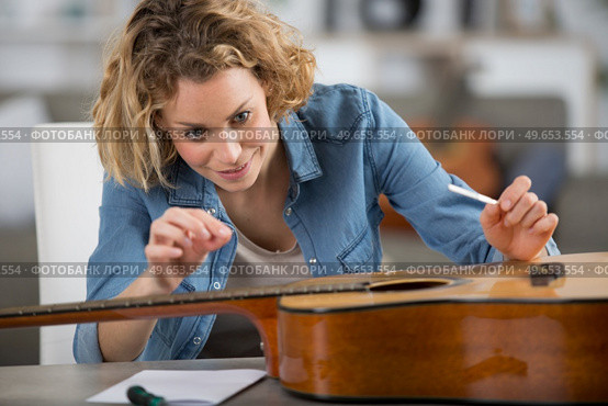 happy woman as luthier apprentice holds string tensioners for reparation. Стоковое фото, агентство Ingram Publishing / Фотобанк Лори