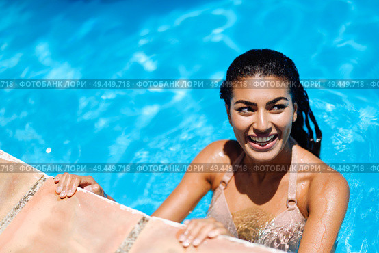 Happy young woman relaxing in swimming pool. Smiling girl with healthy tanned skin and wet hair enjoying Summer Sun at pool edge.. Happy young woman relaxing in swimming pool. Стоковое фото, агентство Ingram Publishing / Фотобанк Лори