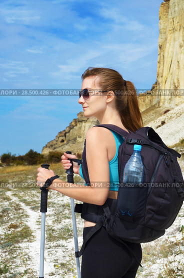 Happy young woman with backpack and trekking poles in mountains. Стоковое фото, фотограф Olena Mykhaylova / Ingram Publishing / Фотобанк Лори