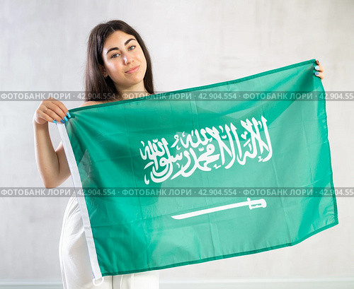 Happy young woman with flag of Saudi Arabia against unicoloured background. Стоковое фото, фотограф Яков Филимонов / Фотобанк Лори