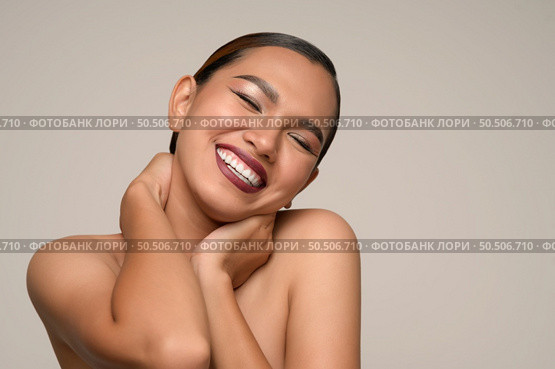 Head shot, portrait of cheerful woman use hand place on neck, hugging herself feelings with toothy smile posing isolated on gray background in studio, copy space. Стоковое фото, агентство Ingram Publishing / Фотобанк Лори