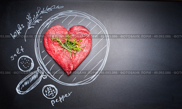Heart shaped chop of meat on black chalkboard with  painted pan and ingredients, top view, place for text. For Meat lovers and eater. Стоковое фото, агентство Ingram Publishing / Фотобанк Лори