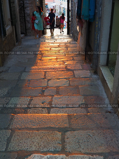 Herceg Novi, Montenegro, old town, Sat-kula tower, Sahat-kula, Tora, chapel tower or Clock tower 08.10.22 Tourists walk along the aisle under the city clock. Sunset, golden hour, summer evening. (2022 год). Редакционное фото, фотограф Юлия Петровская / Фотобанк Лори