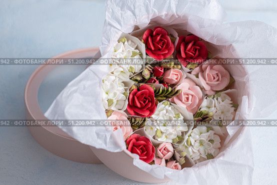 Home-made zephyr floristry arrangement featuring delicate pink, red, and white flowers in a round box with soft tissue paper, showcasing artistic craftsmanship and floral design concept. Стоковое фото, фотограф Ирина Ручушкина / Фотобанк Лори