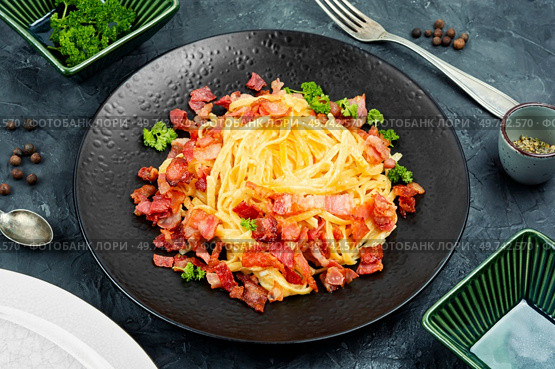 Homemade pasta with roasted bacon, pasta carbonara served on a black plate.. Spaghetti pasta dish with bacon and cheese. Стоковое фото, агентство Ingram Publishing / Фотобанк Лори