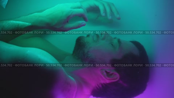 Human cloning - man lies in neon water as an embryo. Стоковое видео, видеограф Илья Шаматура / Фотобанк Лори