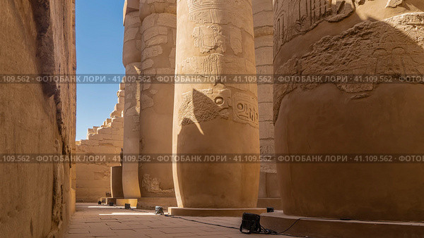 Hypostyle hall of the Karnak Temple in Luxor. Rows of ancient columns and dilapidated walls against the blue sky. Hieroglyphs and carvings are visible. Close-up. Egypt (2021 год). Стоковое фото, фотограф Вера Ивановна Кубарева / Фотобанк Лори