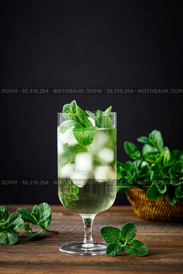 Iced mint tea, refreshing herbal drink in a glass with ice and fresh leaves on dark background. Стоковое фото, агентство Ingram Publishing / Фотобанк Лори
