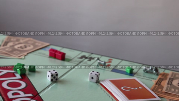 Игра в Монополию. Рука выбрасывает кости. Дубль. (2020 год). Редакционное видео, видеограф Alexzandro / Фотобанк Лори