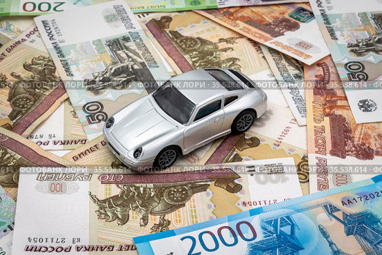 Игрушечный автомобиль стоит на российских деньгах. Автокредит и траты на обслуживание автомобиля. Стоковое фото, фотограф Павел Сапожников / Фотобанк Лори