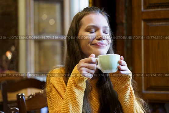 In a beautifully cozy setting filled with warmth and charm, a young woman gently savors a steaming cup of her favorite warm beverage, radiating a sense of deep contentment and profound relaxation. Savoring a Cozy Moment While Enjoying a Warm and Comforting Drink of Your Choice. Стоковое фото, агентство Ingram Publishing / Фотобанк Лори