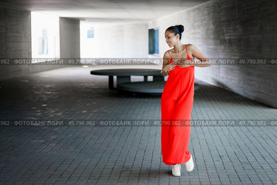 In a striking urban landscape, a graceful dancer enchants the audience while wearing a flowing red dress, performing beautifully amidst the minimalist architecture that frames the moment in time. Beautiful and elegant dance movement in unique urban environments that inspire thought. Стоковое фото, агентство Ingram Publishing / Фотобанк Лори