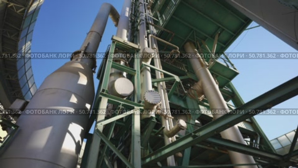 Industrial plant structure with pipes and tanks reaching towards the sky. Стоковое видео, видеограф Данил Руденко / Фотобанк Лори