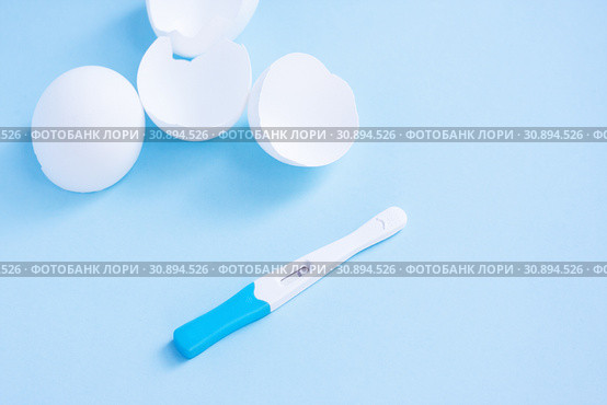 Infertility. Negative pregnancy test and eggshell on blue. Стоковое фото, фотограф Papoyan Irina / Фотобанк Лори