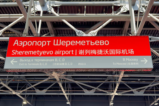 Информационные указатели в аэропорту Шереметьево, Москва. Red sign at Sheremetyevo Airport, exit to Terminals B, C, D. Exit to Moscow city. Convenient informational navigation and markings for tourists and visitors. Редакционное фото, фотограф Ирина Михайличенко / Фотобанк Лори