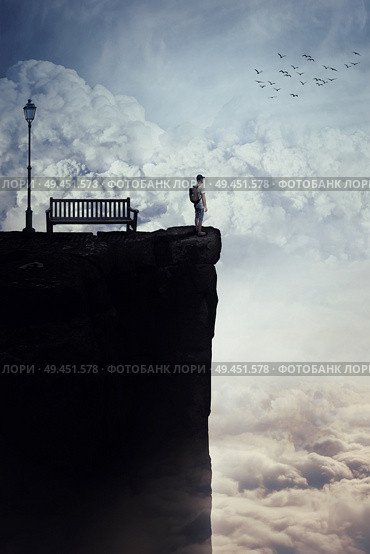 Inspirational imaginary view as a young boy with a bag in his back stand on the peak of a cliff above clouds, looking at the horizon, near a bench and a street lamp. Life journey opportunity concept. Стоковое фото, агентство Ingram Publishing / Фотобанк Лори