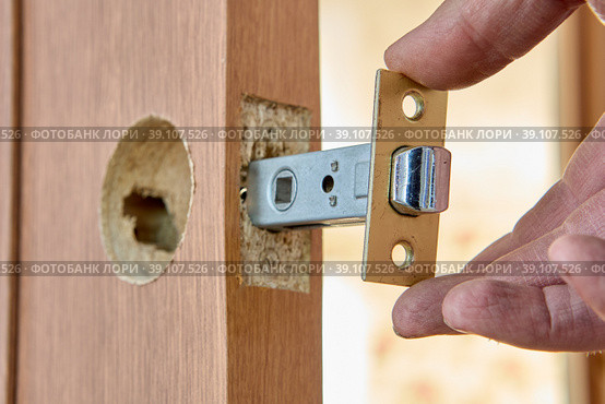 Installing door latch in slot of interior door. Стоковое фото, фотограф Владимир Григорьев / Фотобанк Лори