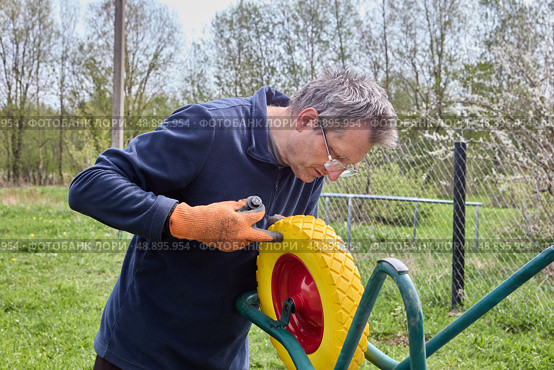 Installing flat free wheel on utility cart to improve durability and reduce maintenance by eliminating risk of tire flats during use. Стоковое фото, фотограф Владимир Григорьев / Фотобанк Лори
