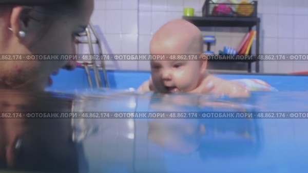 Instructor holding baby underwater during infant swimming lessons. Стоковое видео, видеограф Константин Шишкин / Фотобанк Лори