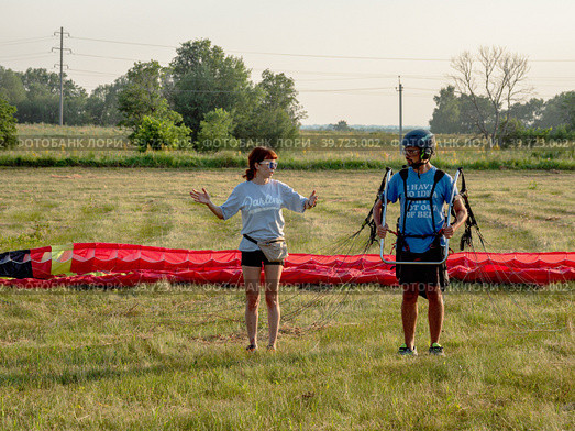 Инструктаж пассажира мотопараплана перед взлётом. Instructing of a paramotor passenger before takeoff. (2022 год). Редакционное фото, фотограф Евгений Романов / Фотобанк Лори
