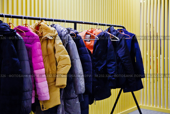 Interior of room storing outdoor clothing for visitors of the establishment, with yellow backgrounds. Wardrobe, many hangers clothes institution, leave outerwear, undress pass into room. Copy space. Стоковое фото, фотограф Aleksandr Golubev / Фотобанк Лори