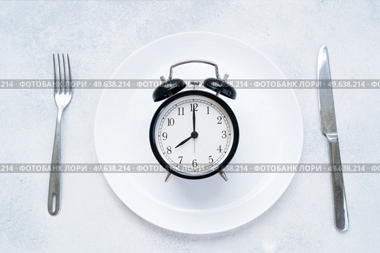 Intermitted farsting diet concept - empty plate with fork and knife and timer. Intermitted farsting diet concept. Стоковое фото, агентство Ingram Publishing / Фотобанк Лори