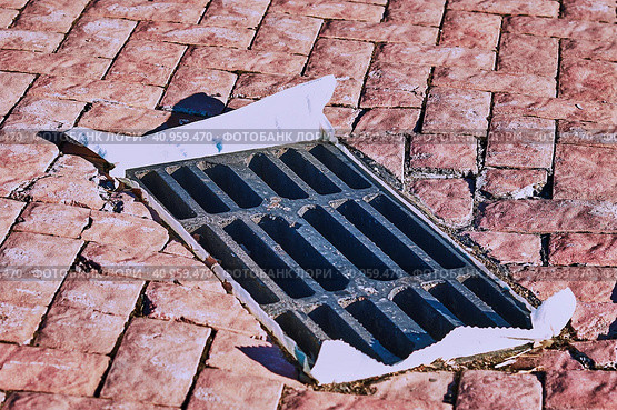 Iron gratings for storm sewers, lined with paving slabs. The hole is closed with a plastic bag in autumn to prevent clogging of underground utilities. The concept of urban critical infrastructure. Стоковое фото, фотограф Алексей Игнатов / Фотобанк Лори