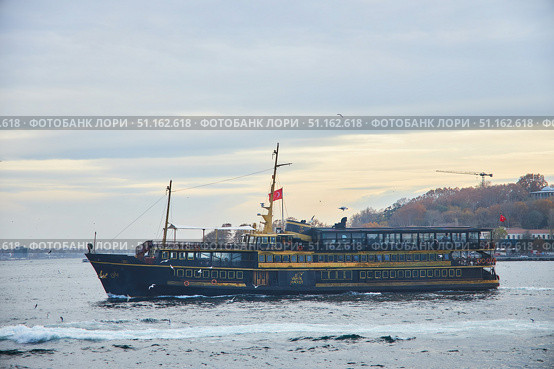 ISTANBUL, TURKEY - NOVEMBER 23, 2021: The Bosphorus Strait. Pleasure boat at sunset. Редакционное фото, фотограф Наталия Кирсанова / Фотобанк Лори