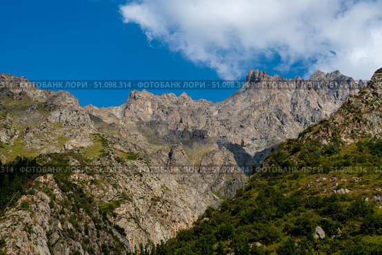 Jagged rock walls, spires, scree, conifer slopes. Scene suggests trekking, scrambling, climbing logistics, basecamp approaches, ridge traverse planning, daytrip possibilities in Ala-Archa Kyrgyzstan. Стоковое фото, фотограф Андрей Ка / Фотобанк Лори