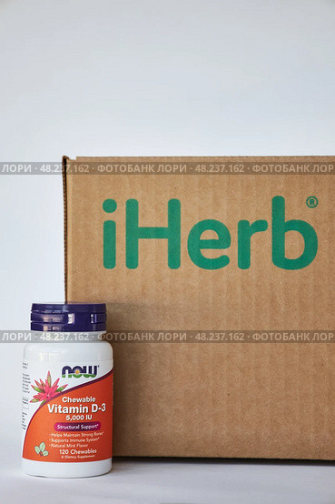Jar of vitamin D3 NOW Foods Company, near iHerb Brown Cardboard box. Редакционное фото, фотограф Екатерина Якименко / Фотобанк Лори