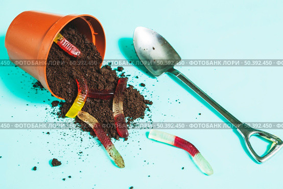 jelly worms overturning pot with ground near shovel. Стоковое фото, агентство Ingram Publishing / Фотобанк Лори