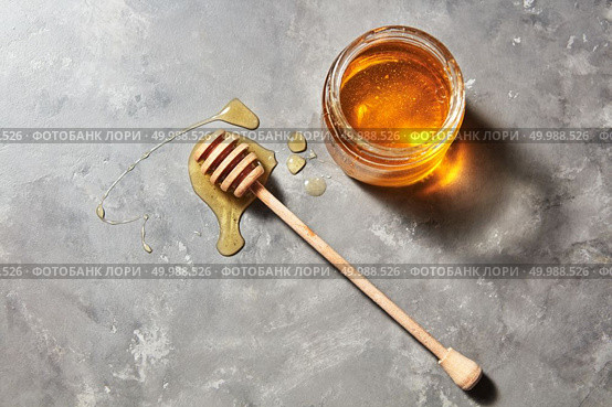 Jewish holiday Rosh Hashanah background with organic floral honey on a gray stone background, copy space. Top view. Pure natural sweet goodness.. Sweet flower natural honey in a jar and wooden spoon on a gray concrete table. Top view. Jewish New Year healthy holiday. Стоковое фото, агентство Ingram Publishing / Фотобанк Лори