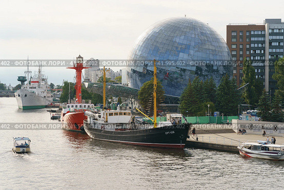 Kaliningrad, Russia - August 22, 2022:  Museum of the World Ocean. Building is in form of glass ball. Irbensky floating lighthouse. Moored on Pregolya River. SRT-129 is medium fishing trawler. Редакционное фото, фотограф YuryKara / Фотобанк Лори