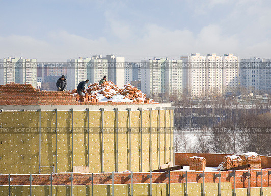 Каменщики кладут кирпичный парапет на фоне городских жилых массивов. Стоковое фото, фотограф Владимир Чинин / Фотобанк Лори